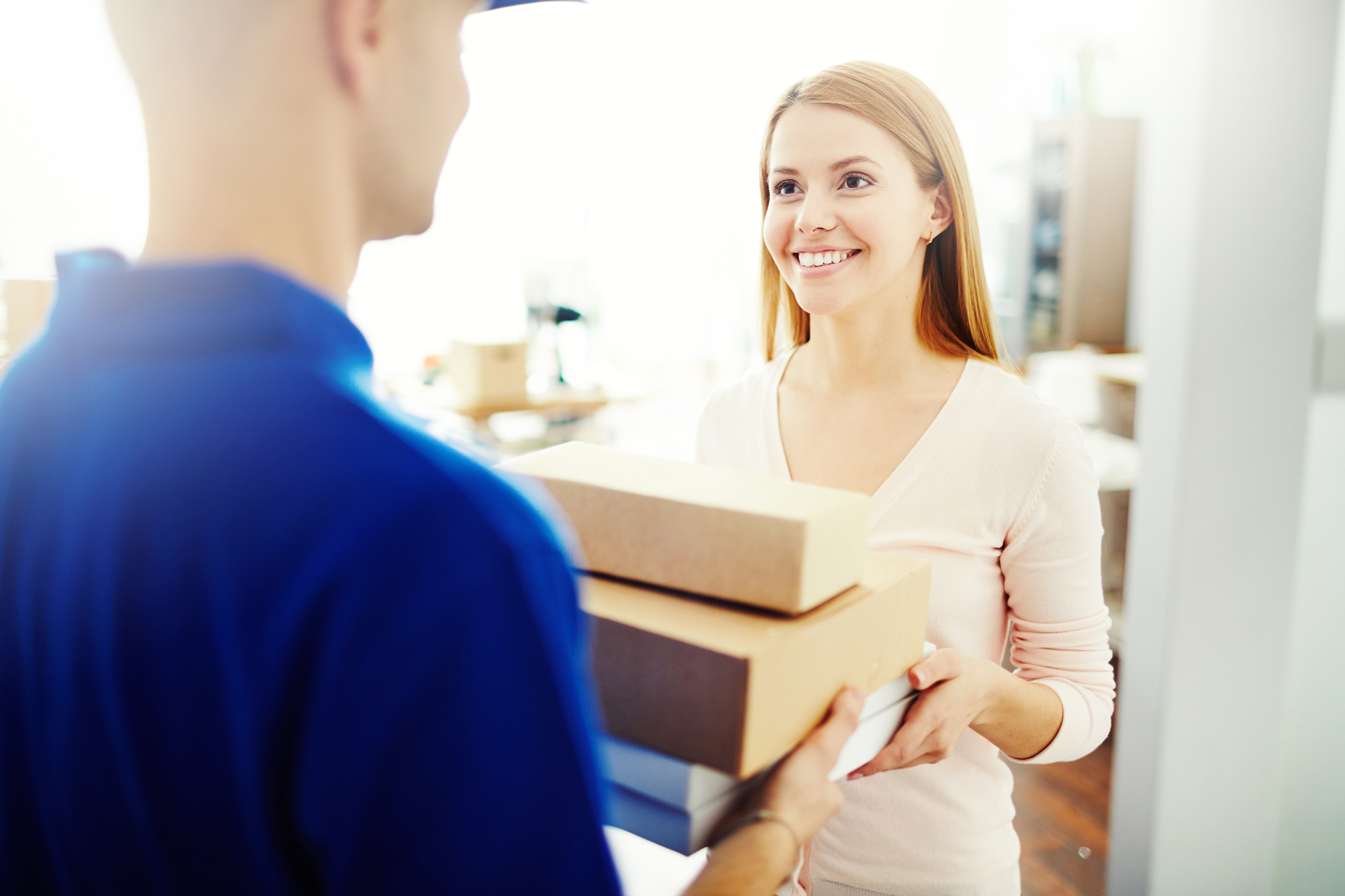 Happy young woman receiving a box from mailman